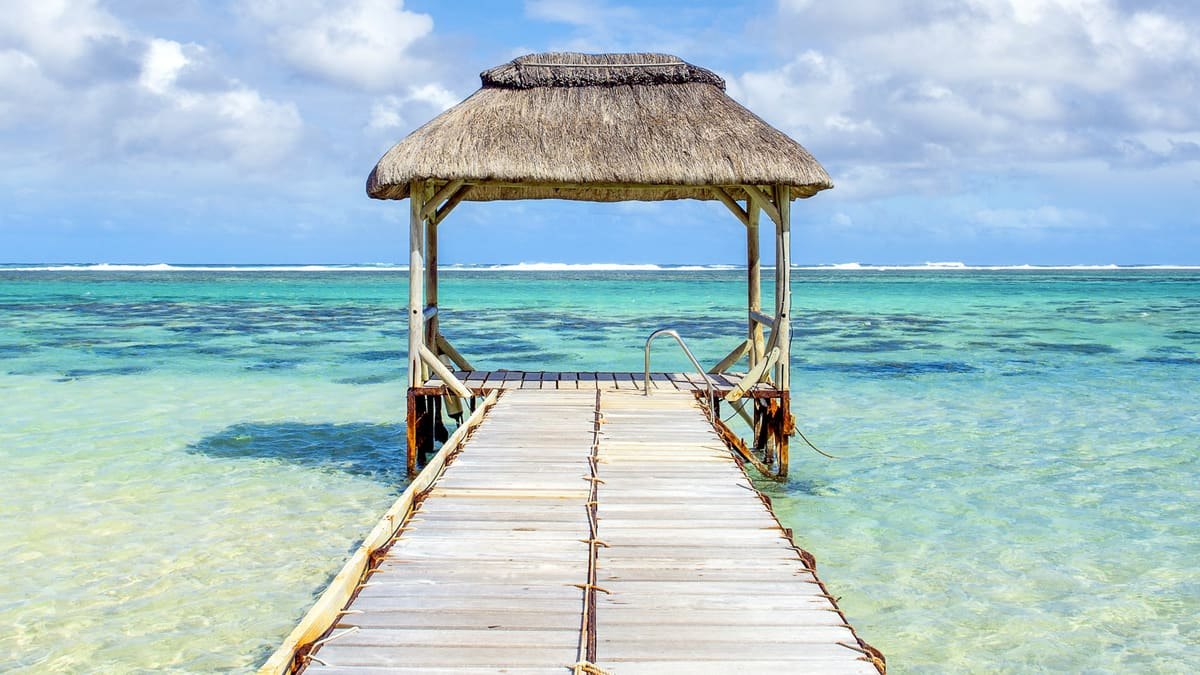 ponton lagon ile maurice Un ponton de bois sous un toit de chaume avançant sur le lagon de l'île Maurice